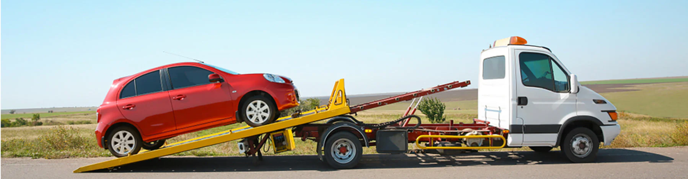a small red car being towed on a white recovery truck using taut straps