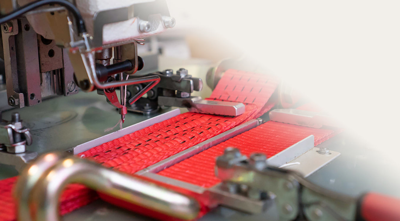 An industrial machine sewing black detailing onto a red taut strap